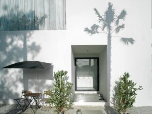 a white building with a palm tree in front of it at HER HUAHIN POOL VILLA in Hua Hin