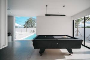 a black pool table in a room with a swimming pool at HER HUAHIN POOL VILLA in Hua Hin