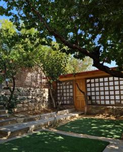 a garden with a stone wall and a wooden gate at safari house in Tbilisi City