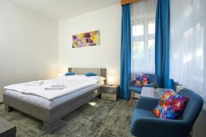 a bedroom with a bed and two blue chairs at Penzion Vila Tereza in Hranice