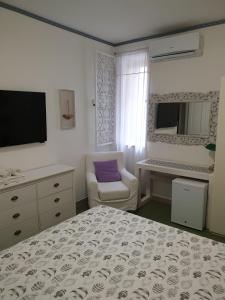 1 dormitorio con 1 cama, 1 silla y TV en Kalimaka Bed & Breakfast, en Scario