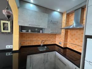 una cocina con armarios de acero inoxidable y fregadero en Spacious Apartment with 3 pools very central, en Benalmádena