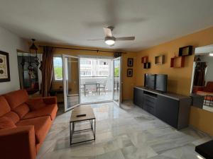 Una sala de estar con un sofá y un televisor. en Spacious Apartment with 3 pools very central, en Benalmádena