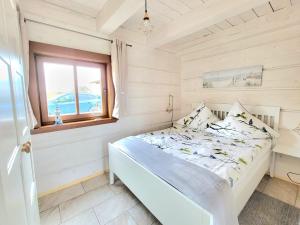 a white bedroom with a bed and a window at KOPUVA in Nidden