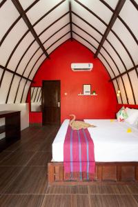 Un dormitorio con una pared roja y una cama en Kidi's Lodge Gilitrawangan, en Gili Trawangan