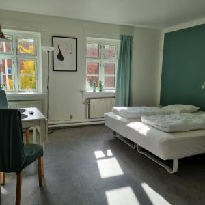 a bedroom with two beds and a desk and windows at Danhostel Ringsted in Ringsted