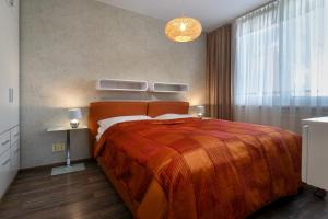 a bedroom with a large bed with a orange blanket at TATRYSTAY Apartment Smrek in Vysoke Tatry - Strbske Pleso