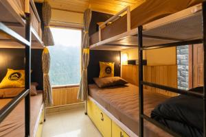 two bunk beds in a room with a window at The Hosteller Shoja, Jibhi in Jibhi