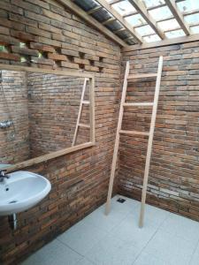 un bagno con un lavandino e una scala su un muro di mattoni di omah kayu jagalan a Magelang