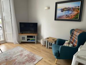 a living room with a tv and a blue chair at Newton Croft Tenby overlooking North Beach in Tenby