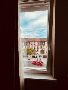 a window with a view of a red car outside at Hotel Residenz in Ansbach