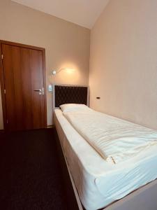 ein großes weißes Bett in einem Zimmer mit einer Tür in der Unterkunft Hotel Residenz in Ansbach