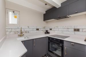 uma cozinha com armários cinzentos e um lavatório em The Oak Rooms - Stylish & luxurious stay in Sussex by Huluki Sussex Stays em Hurstpierpoint