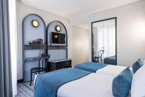 a hotel room with two beds and a desk at Hôtel de France Gare de Lyon Bastille in Paris