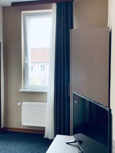 a bedroom with a large window and a television at Hotel Residenz in Ansbach
