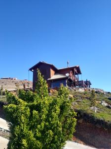 uma casa no topo de uma colina com uma árvore em Chalé Guadalupe - Condomínio Altos da Serra em Bom Jardim da Serra