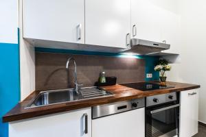 una cocina con fregadero de acero inoxidable y armarios blancos en Stylish designed apartment in a calm district en Viena