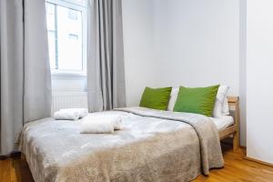 Un dormitorio con una cama con almohadas verdes y una ventana en Stylish designed apartment in a calm district en Viena