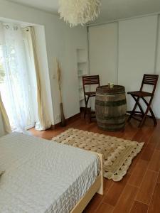 ein Schlafzimmer mit einem Bett, einem Fass und Stühlen in der Unterkunft Aux Chambres du Chadoux de Chateaubourg (ChaChaCha) in Châteaubourg