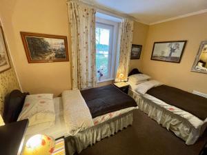 two beds in a room with a window at APSLEY VILLA GUEST HOUSE. in Cirencester