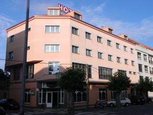 a large pink building with a hotel sign on it at Hotel Restaurante Pizzeria ABC in Laracha