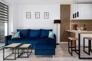 a living room with a blue couch and a table at Apartments Nad Parsętą Młyńska by Renters in Kołobrzeg