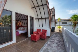 Un balcón con sillas rojas, una cama y un dormitorio. en Kidi's Lodge Gilitrawangan, en Gili Trawangan