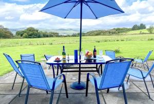 a table with chairs and an umbrella on a patio at Kennacraig Lodge in Whitehouse
