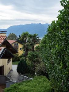 a view of a house with palm trees and mountains at Amazing 3 bedrooms villa with lavish garden, breathtaking lake and mountains view in Luino