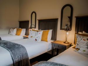Bontebokskloof Manor في سويلندام: غرفة نوم بسريرين وطاولة بها مصباح