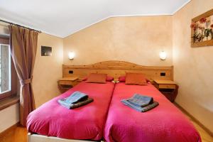 een slaapkamer met een groot rood bed met handdoeken erop bij Baita Aris Appartamento Ables in Livigno