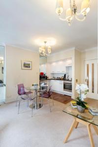 a living room with a table and chairs and a kitchen at Park Lane Apartments - Clarges Street in London