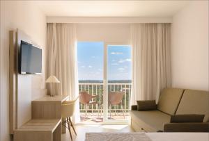 ein Wohnzimmer mit einem Sofa und einem Fenster mit einem Balkon in der Unterkunft Hotel Castell dels Hams in Porto Cristo