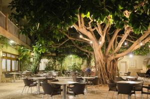 ein Restaurant mit Tischen und einem Baum in der Mitte in der Unterkunft Hotel Castell dels Hams in Porto Cristo