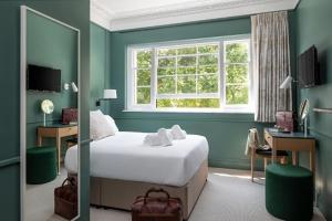 a bedroom with a bed and a desk and a window at The Goodenough Hotel London in London