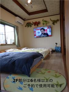 um quarto com uma cama e uma televisão na parede em BBQ可 1日1組限定 貸切別荘 秘密基地 は恐竜博物館まで3km スキージャム勝山まで12km em Katsuyama