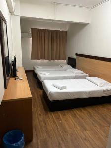 a row of four beds in a room at Hotel 75 Temerloh in Temerloh