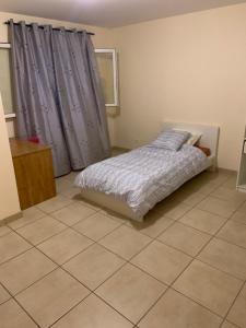 um quarto com uma cama e piso em azulejo em klm em Roussillon en Isere