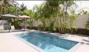 a swimming pool in a yard with umbrellas at Kaz Vavang magnifique villa 4 ETOILES piscine chauffée in Étang-Salé les Bains