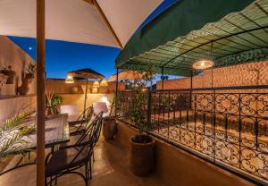 a balcony with a table and chairs and an umbrella at Riad Oumnia - Top emplacement - Riad en entier pour vous in Marrakesh