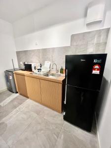 eine Küche mit einem schwarzen Kühlschrank und einer Spüle in der Unterkunft Imperio Residences Private Bathtub or Jacuzzi by Nestcove in Malakka