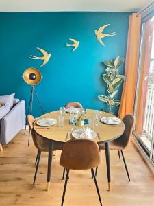 サン・ジェルマン・アン・レーにあるAppartement spacieux hyper centre Saint Germainのダイニングルームテーブル(椅子付)、壁に鳥 +18枚の写真