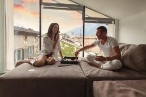 a man and a woman sitting on a couch with a laptop at HEART OF TRENTO Loft & Rooms in Trento