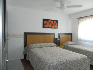 a bedroom with two beds and a television in it at Hotel Adriatico in Mar del Plata