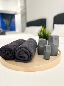 a wooden tray with towels and speakers on a bed at Imperio Residences Private Bathtub or Jacuzzi by Nestcove in Melaka