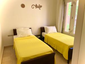 2 camas en una habitación con sábanas amarillas en South marina apartment MS10 Wi-Fi available en Hurghada