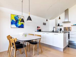 una cucina con armadi bianchi, tavolo e sedie di 4 person holiday home in Bogense a Bogense