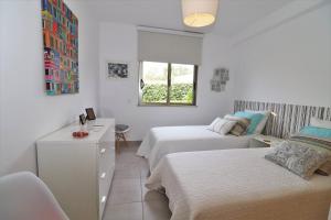 Habitación blanca con 2 camas y ventana en Albufeira Modern Condominium Vitismar With Pool, en Guia