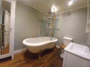 a bathroom with a bath tub and a sink at Elegant & spacious parkside 2-bedroom 2-bathroom flat in period building opposite Blackheath Common - private entrance, great Greenwich location! in London