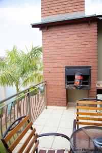 a brick fireplace on a balcony with tables and chairs at Palm Valley Inn in Hartbeespoort